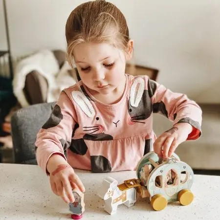 girl playing little wooden disney toys in hotel room