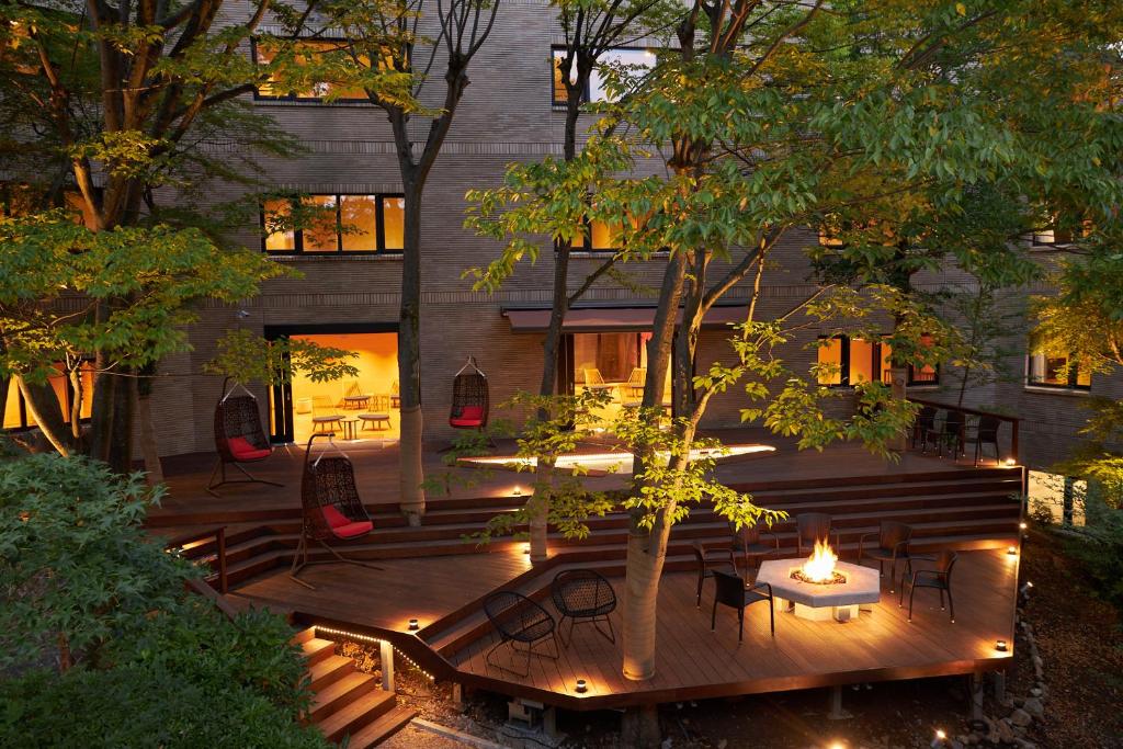 Hakone Yutowa courtyard terrace with trees, hanging chairs, and a fire pit at dusk
