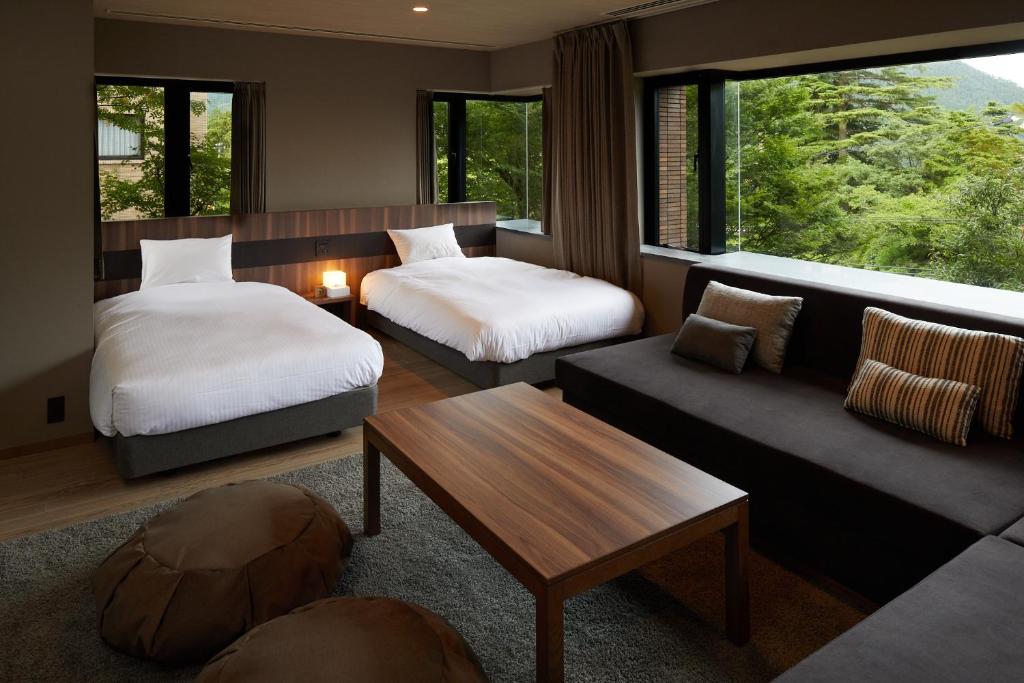 Guest room at Hakone Yutowa with twin beds, sofa seating, and forest views