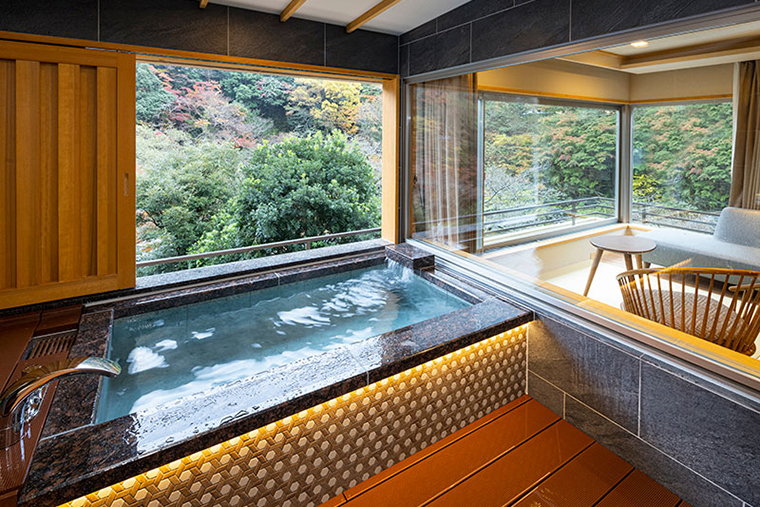 Private open-air hot spring bath at Hotel Okada overlooking forested hills