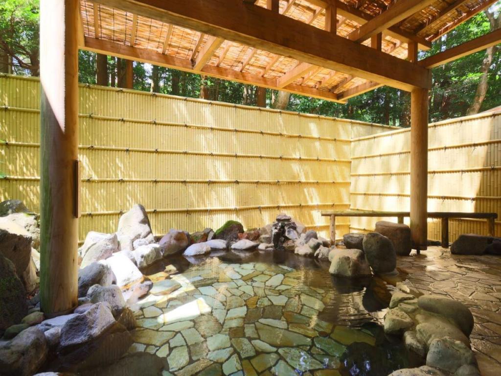 Outdoor hot spring bath at Mizu no Oto surrounded by rocks, bamboo screening, and trees