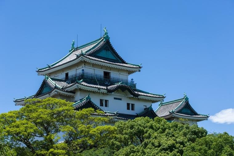 White Wakayama Castle tower rising above green Torafusuyama hill